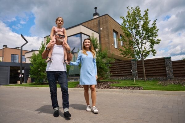 Photo of happy family on background of cottage and pines. Moving to new home